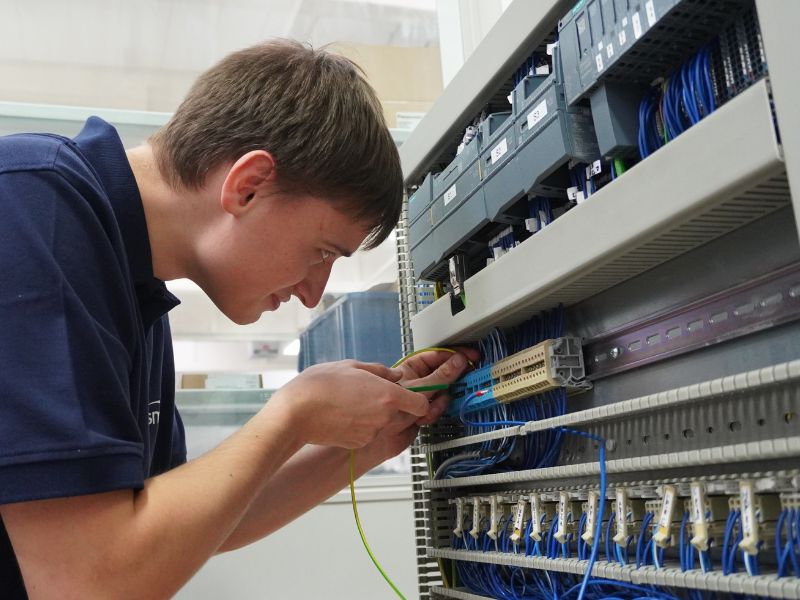 Sorgfältiges Verdrahten in der Mechatronik-Ausbildung Auszubildender verdrahtet Steuerungselemente in einem Schaltschrank